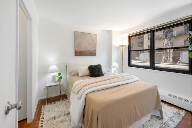 bedroom with baseboard heating, wood finished floors, and baseboards