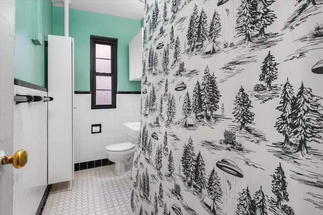 bathroom with tile patterned floors, wainscoting, toilet, and tile walls