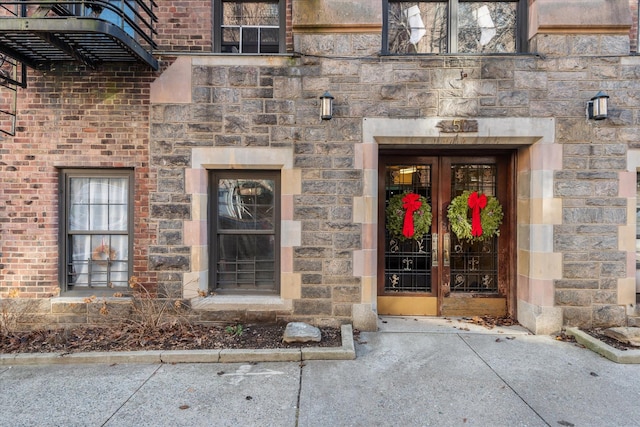 doorway to property with brick siding, french doors, and stone siding