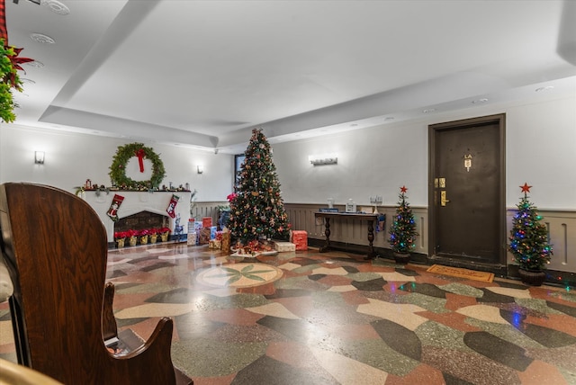 interior space with a tray ceiling, a fireplace, and wainscoting