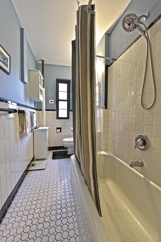 bathroom with shower / bathtub combination with curtain, toilet, tile walls, and wainscoting