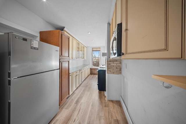 kitchen featuring stainless steel appliances, brown cabinets, light countertops, and light wood-style flooring