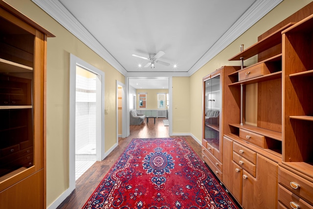 corridor with dark wood finished floors, crown molding, and baseboards