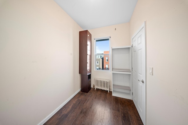 corridor with baseboards, radiator heating unit, and wood finished floors