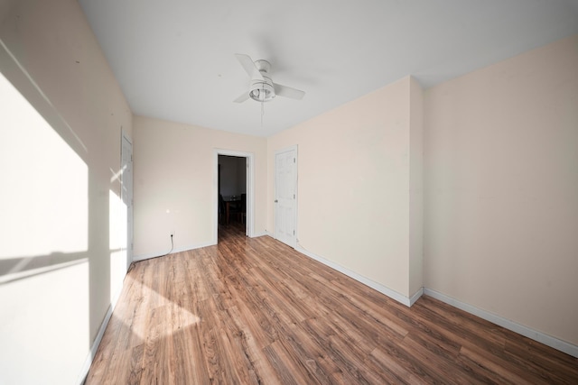 empty room with ceiling fan, wood finished floors, and baseboards