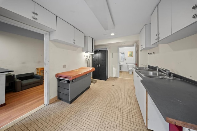 kitchen with white cabinets, sink, and light tile patterned floors