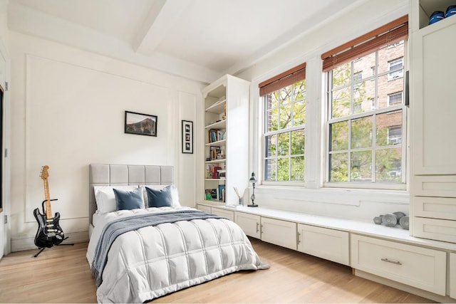 bedroom with beam ceiling and light wood-type flooring