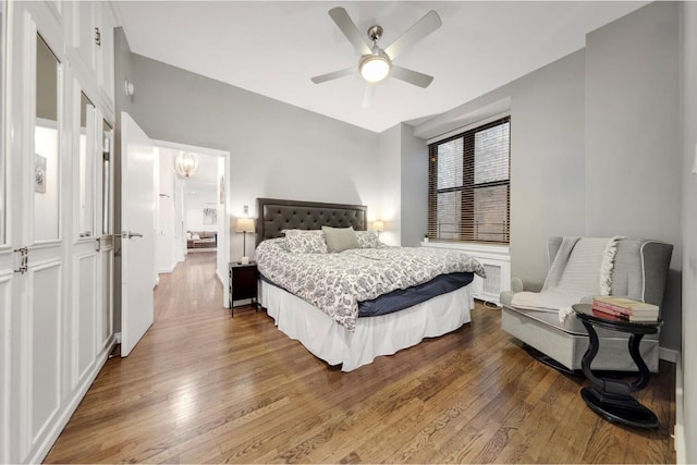 bedroom with ceiling fan with notable chandelier and hardwood / wood-style flooring