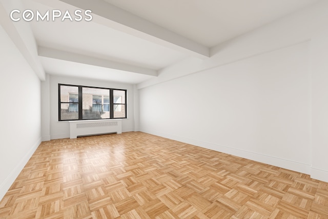 spare room with radiator, baseboards, and beam ceiling