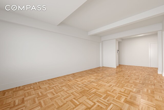 unfurnished room featuring baseboards and beam ceiling