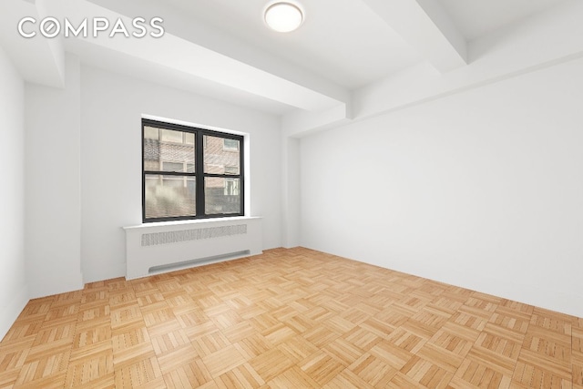 empty room with light parquet flooring, beamed ceiling, and radiator