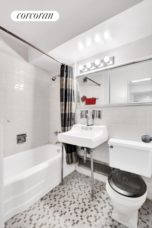 bathroom with decorative backsplash, shower / tub combo with curtain, tile walls, and toilet