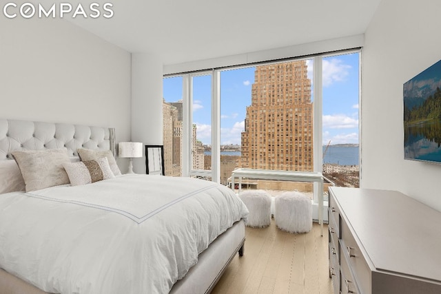 bedroom featuring a wall of windows, light hardwood / wood-style flooring, and multiple windows