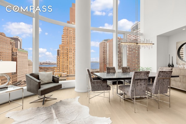 dining room featuring a water view, wood finished floors, a towering ceiling, and a city view