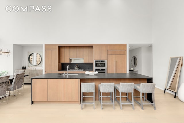 50 W St Unit 14B, New York City, NY 10006 - kitchen featuring dark countertops, appliances with stainless steel finishes, a towering ceiling, a sink, and a kitchen bar