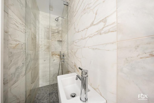 bathroom with a marble finish shower and tile walls