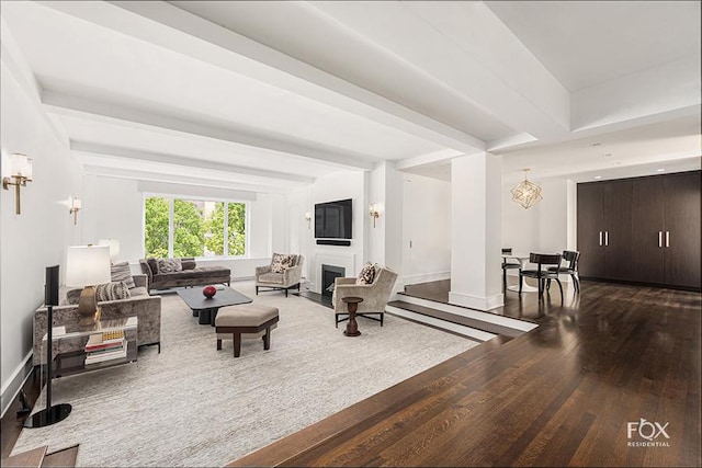 living room featuring beamed ceiling, a fireplace, wood finished floors, and baseboards