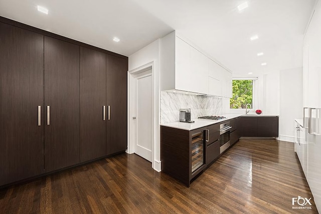 kitchen featuring dark wood-style flooring, stainless steel appliances, light countertops, a sink, and dark brown cabinets