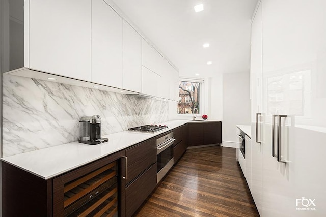 kitchen with stainless steel appliances, white cabinets, dark brown cabinets, light countertops, and modern cabinets