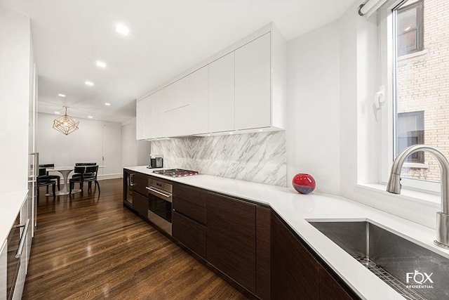 kitchen featuring a sink, appliances with stainless steel finishes, modern cabinets, dark brown cabinetry, and dark wood-style floors