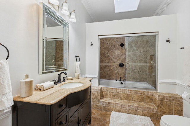 full bathroom featuring toilet, tile patterned flooring, tiled shower / bath, crown molding, and vanity