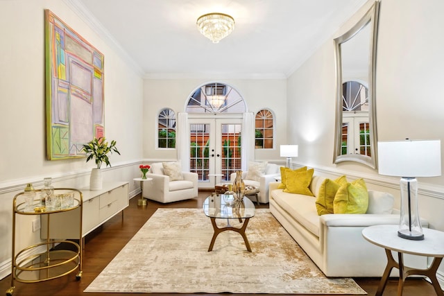 living area with a wainscoted wall, ornamental molding, french doors, dark wood-style flooring, and a notable chandelier