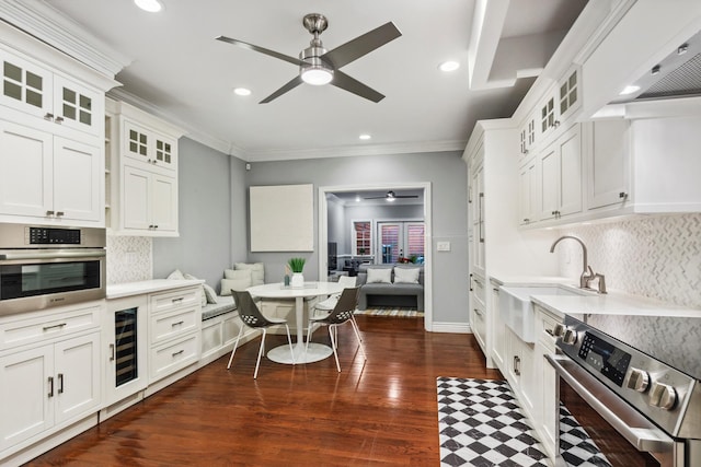 kitchen with beverage cooler, dark wood-style floors, ceiling fan, stainless steel appliances, and light countertops