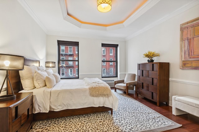 bedroom featuring a raised ceiling, wood finished floors, and crown molding