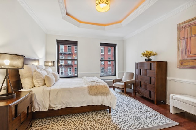 bedroom with a tray ceiling, crown molding, and wood finished floors