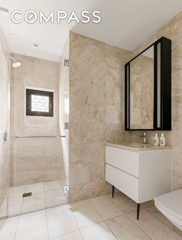 bathroom featuring tile walls, vanity, toilet, and an enclosed shower