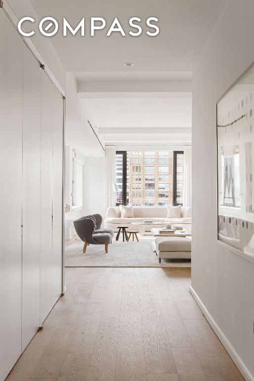 corridor featuring beam ceiling and light wood-type flooring