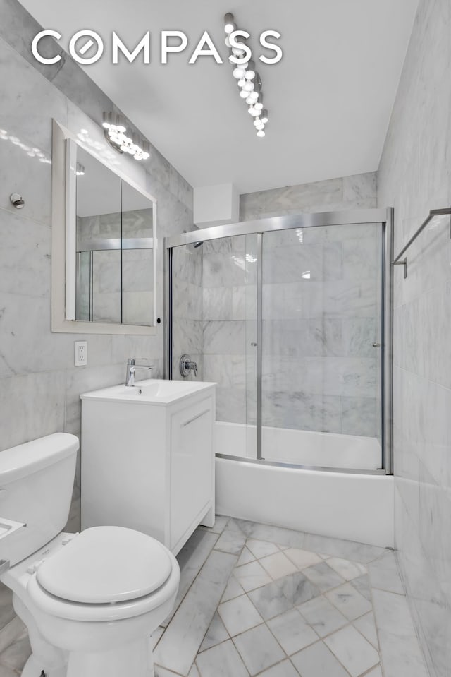 155 E 38th St Unit 18E, New York City, NY 10016 - bathroom with vanity, shower / bath combination with glass door, toilet, marble finish flooring, and tile walls