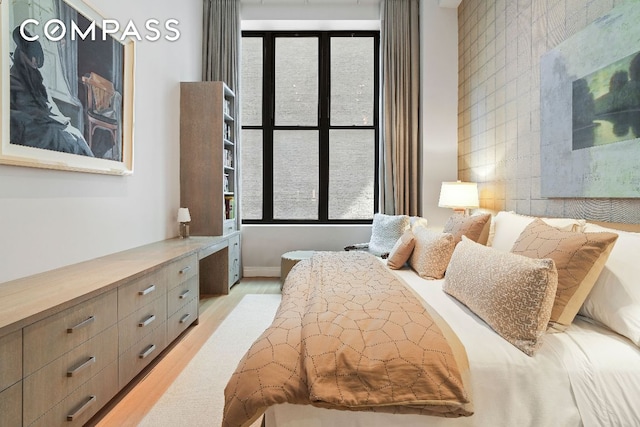 bedroom featuring light wood finished floors, tile walls, and built in study area