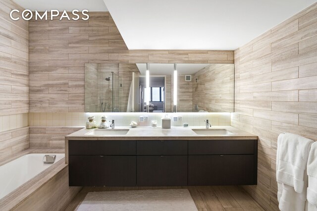 421 Hudson St Unit 221, New York City, NY 10014 - bathroom with double vanity, a stall shower, a bath, and tile walls