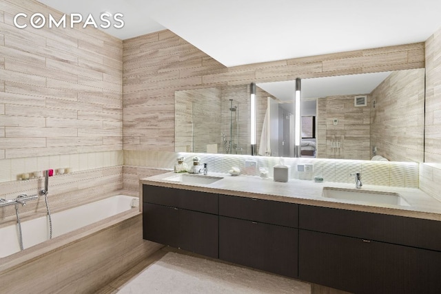 bathroom with double vanity, a garden tub, and a sink