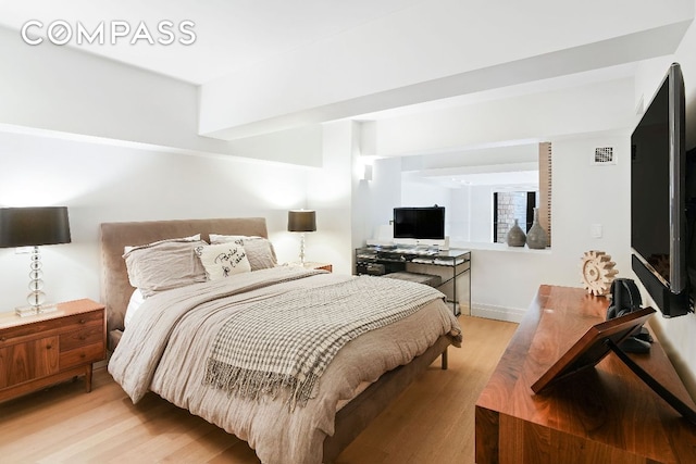 bedroom with light wood-style floors and visible vents