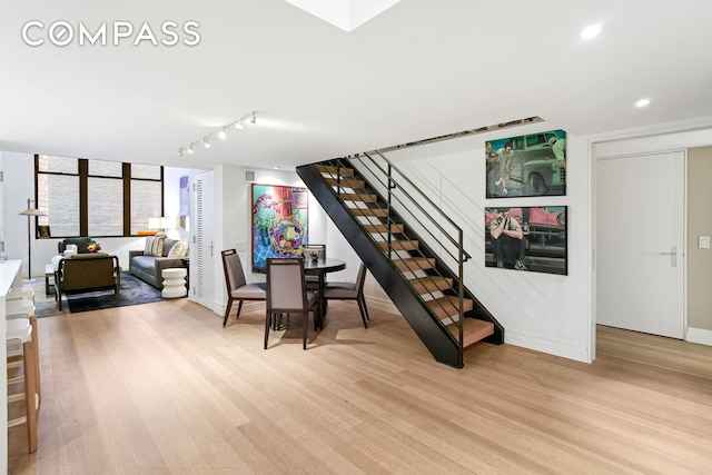 dining area featuring track lighting, recessed lighting, stairway, and light wood finished floors