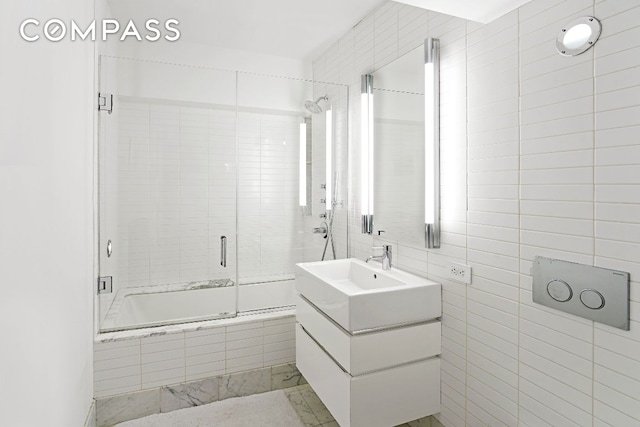 full bath featuring tiled shower / bath, vanity, and tile walls