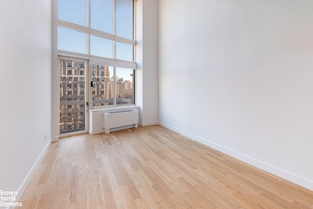 spare room featuring radiator and light hardwood / wood-style floors