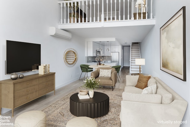 living room featuring a wall mounted air conditioner, light hardwood / wood-style floors, and a high ceiling