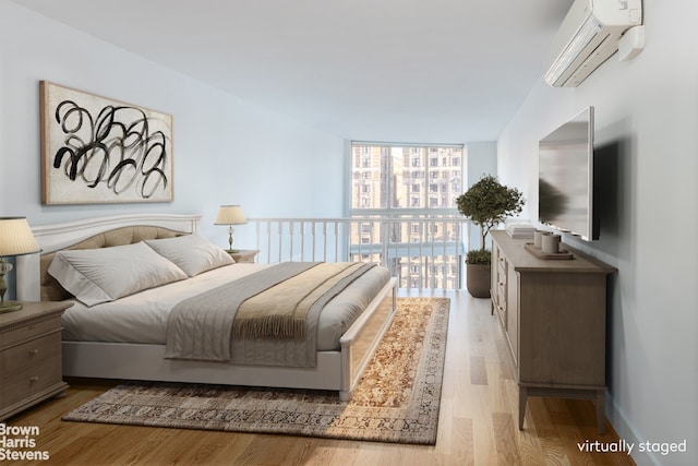 bedroom featuring expansive windows, a wall unit AC, and light hardwood / wood-style flooring