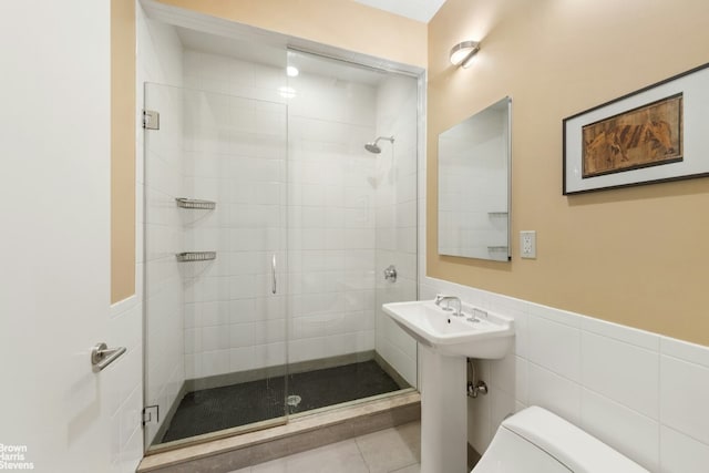 bathroom with toilet, tile walls, tile patterned floors, and an enclosed shower