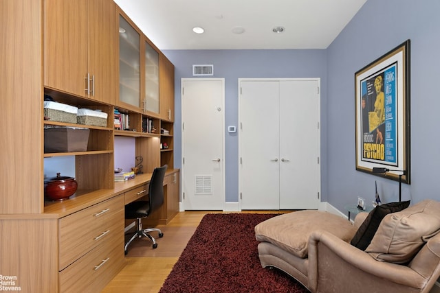 home office with built in desk and light wood-type flooring