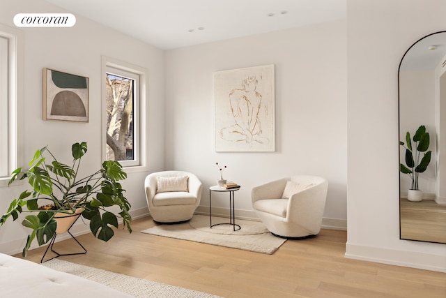 living area featuring baseboards, visible vents, and light wood finished floors