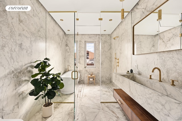 bathroom featuring marble finish floor, stone wall, a freestanding tub, and vanity