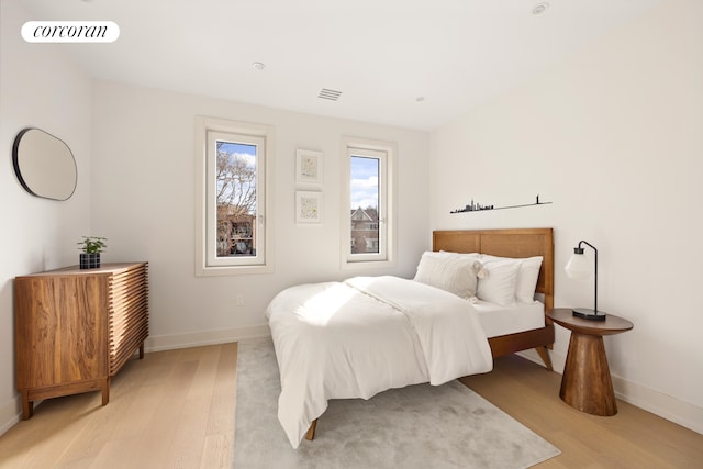 bedroom featuring light wood-style flooring, visible vents, and baseboards