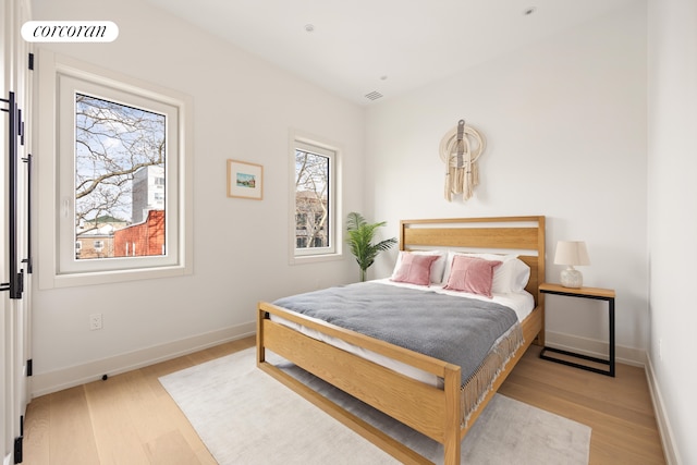 bedroom with baseboards, visible vents, and light wood-style floors