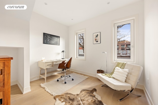 home office with light wood finished floors, visible vents, and baseboards