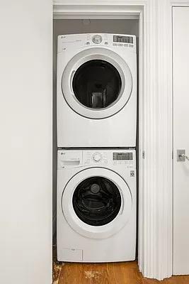 clothes washing area with stacked washer / drying machine and hardwood / wood-style floors