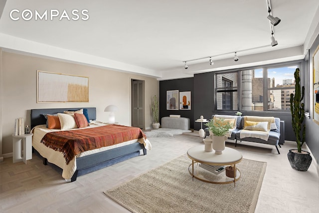 bedroom with track lighting, a view of city, and baseboards